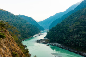 Fototapeta na wymiar Spectacular view of the sacred Ganges river flowing through the green mountains of Rishikesh, Uttarakhand, India.