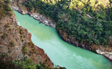 Obraz premium Spectacular view of the sacred Ganges river flowing through the green mountains of Rishikesh, Uttarakhand, India.