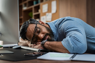 Tired businessman sleeping on computer desk