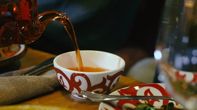 Pouring freshly brewed tea in ornamental cup