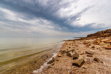 The sea shore with the stony beach and the stormy cloudy sky. Taganrog bay, Azov sea, Russia