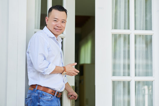 Portrait of young smiling real estate agent inviting clients home