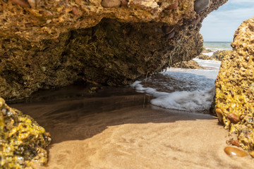 Sea water passing between rocks on the beach of the Namibe Desert. Angola. Africa.