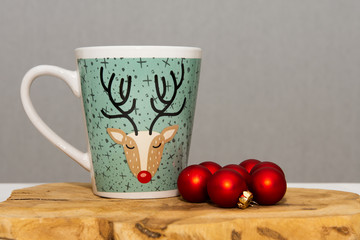 Christmas balls next to a cup.