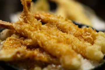 Tempura (deep-fried Fish and vegetables) served over a bowl of rice on a table in traditional Japanese restaurant (Tempura bowl is called Tendon)