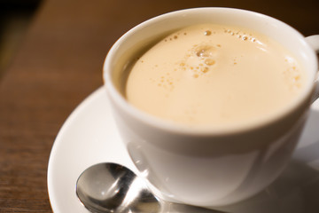 White porcelain cup of milk tea (tea with milk isolated) with teaspoon on a table (a cafe in Jimbocho, Tokyo)