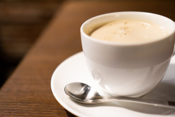 White porcelain cup of milk tea (tea with milk isolated) with teaspoon on a table (a cafe in Jimbocho, Tokyo)