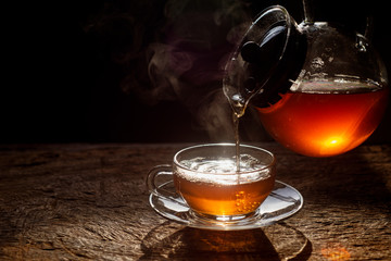 The tea is being poured from the bright colored teapot