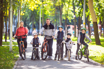 Obraz premium Theme family active sports outdoor recreation. A group of people is a big family of 6 people standing posing on mountain bikes in a city park on a road on a sunny day in autumn