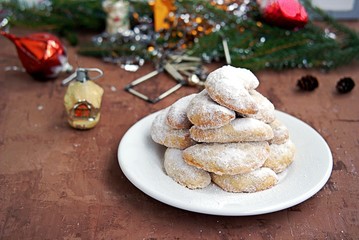 Shortbread with walnuts, covered with powdered sugar, on a white plate in the New Year and Christmas style. Merry christmas and happy new year concept.