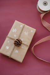 Christmas gift box on burgundy,  marsala color background. Christmas present with handmade decoration. Close up. Copy space