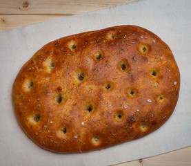 Traditional Italian focaccia homemade bread on lianna napkin. Wooden background. View from the top.