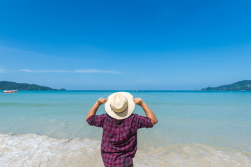 happy travel woman stand on sand of the sea with blue sky at sunny day. subject is blurred.