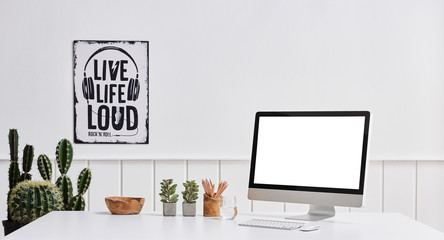 Desktop technological tool computer screen white desk and vase of plant.