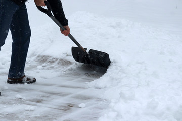 Winter snowy day background. Man shoveling snow on driveway during a heavy snowfall. Close up composition.