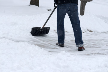 Winter snowy day background. Man shoveling snow on driveway during a heavy snowfall. Close up composition.