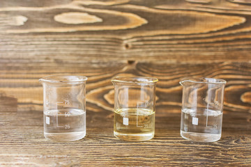 Three tubes of water, oil and alcohol on the background of boards.
