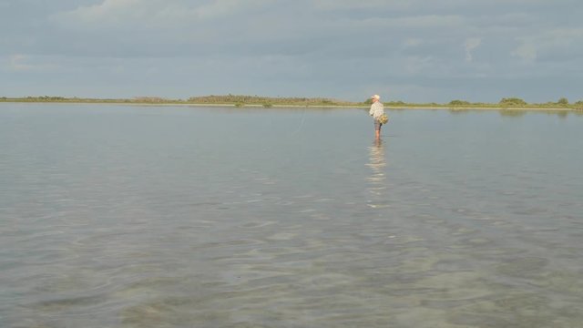Man wading in a flat lagoon fishing for bonefish