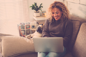 beautiful blonde curly woman working at home with a laptop internet connected while her best...