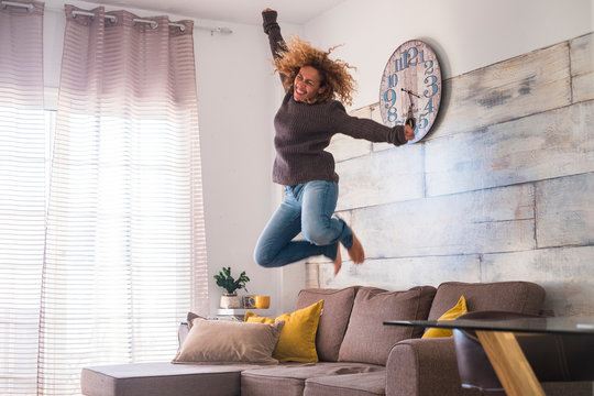 Crazy Middle Age Woman Jump At Home Over The Sofa To Celebrate Success - Joyful And Happiness People Concept - Craziness And Freedom Lifestyle For Independent Modern Female