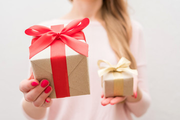 Woman holding a box with a gifts, gift with red ribbon, gift with gold ribbon, on camera, front view, close up