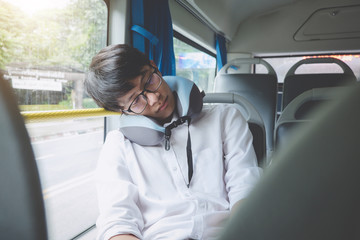 Young Asian man traveler sitting on a bus and sleeping with pillow, transport, tourism and road...