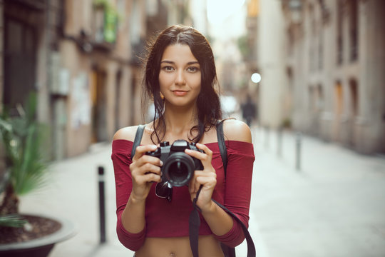 Attractive tourist woman photographer with dslr camera looking at camera outdoor in city street in Barcelona, Spain. Gorgeous happy mixed race Asian Caucasian female in casual hipster clothes with