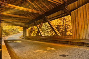 sun shining through covered bridge fall colors