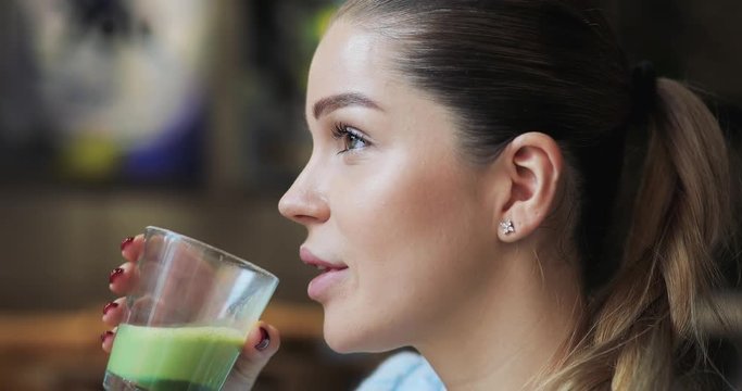 Woman drinking matcha latte in cafe