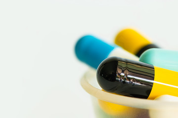 Close-up photo of the colorful pills in a cup isolated on white background