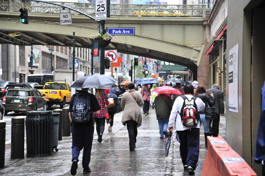 People walk towards Grand Central station with umbrellas in the rain