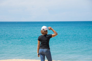 happy travel woman stand on sand of the sea with blue sky at sunny day. subject is blurred.