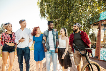 Multi-ethnic group of people going with their male friend to bmx contest in the urban summer park,...