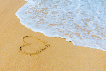 heart shape on sand at the sea sunny day. subject is blurred.