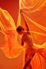 Young graceful female ballet dancer or classic ballerina dancing at red studio. Caucasian model on...