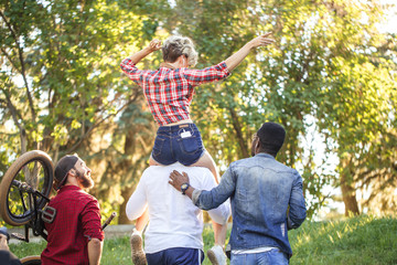Rear view of unrecognized multiracial people going at the park in summer afternoon. Boyfriend...
