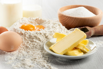 Ingredients for dough and pastry on wooden table, close up on butter.