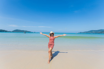 happy travel woman stand on sand of the sea with blue sky at sunny day. subject is blurred.