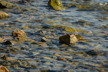 Sea stones and rocks of different sizes and texsture of black, gray and brown under the water on the Black Sea coast as nature bacground. Excellent concept for any design