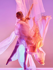 Young graceful female ballet dancer or classic ballerina dancing at pink studio. Caucasian model on...