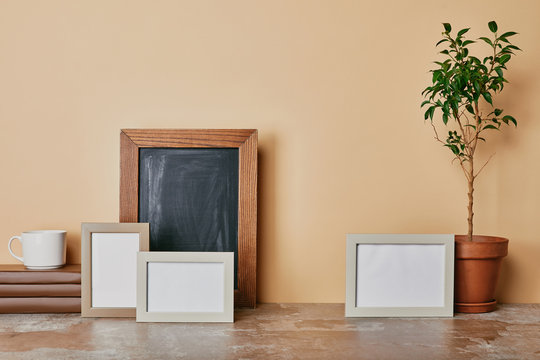 Ohoto frames, books, plant and cup of coffee on table on beige background