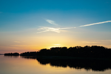 Fototapeta premium A beautiful blue sky at sunset accented by a white spangled cloud, a few days after midsummer, viewed from a cove on the Island of Nicklösa in the Åland Islands, Finland.