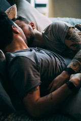 Caucasian homosexual family in bed before sleep. Handsome hot man with bristle kissing good night...