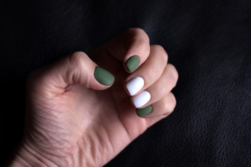 The green white manicure  on black background. Isolated fashion concept.