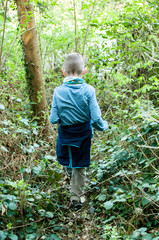 Child explores a wild overgrown path in the forest