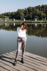 Portrait of beautiful woman near a wooden bridge by the lake at sunny day. Atmospheric portrait of a lonely girl walking