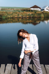 Portrait of beautiful woman near a wooden bridge by the lake at sunny day. Atmospheric portrait of a lonely girl walking