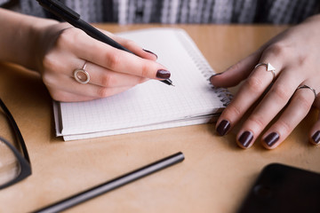 Fototapeta premium Woman hand writing note pad on wood table in coffee shop
