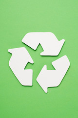 Top view of white trash recycle sign with arrows on green background