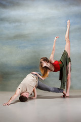 Two people dancing in contemporary stile of ballet at studio on gray